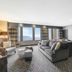 Hilton Motif Seattle suite with city and water views, gray sofa, chairs, and dining area