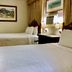 Casa del Caribe Inn in San Juan guest room with two beds, nightstand lamps, and framed wall art