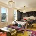 The Hotel Chelsea in New York suite with city-view windows, dark kitchen cabinetry, and colorful decor
