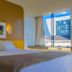 Luxor Soft Hotel Teresina guest room with king bed, wall art, and city view through large window