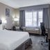 Ramada by Wyndham Thunder Bay Airlane Hotel guest room with king bed, desk, lounge chair and window view