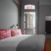 Hotel Saint Vincent room in New Orleans with pink floral pillows, gray walls and wooden floor