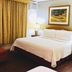 Casa del Caribe Inn in San Juan guest room with bed, armchair, ottoman, lamp, and framed wall art