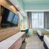 Canario Lagoon Hotel San Juan guest room with two beds, desk, wall TV and large window