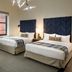 Hotel Indigo Boston Garden Boston guest room with two beds, sofa, ottoman, and city-view windows