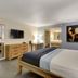 Thunderbird Boutique Hotel in Las Vegas guest room with king bed, dresser, wall TV and bathroom vanity