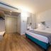 Airport Hotel Bergamo Bagnatica guest room with double bed, wood floors, and wall-mounted lights