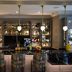 voco St. James Hotel by IHG New Orleans bar with backlit liquor shelves and colorful upholstered stools