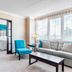 Four Points by Sheraton London suite with bedroom, sitting area, blue chair, sofa, and large window