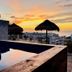 Flamingo Hotel, Cozumel: poolside ocean view at sunset with palapa umbrellas and stone wall