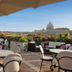 Atlante Garden Hotel Rome rooftop terrace with tables, umbrellas, flowers and St. Peter's Basilica view