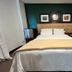 Sj Suites Hotel San Juan guest room with king bed, dark green accent wall, and framed art