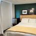 Sj Suites Hotel San Juan guest room with king bed, green accent wall and bedside tables