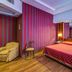 Atlante Garden Hotel Rome guest room with bed, mirrored headboard, striped wall, and armchair