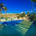 Araiza Palmira in La Paz with a tennis court, palm trees, and hillside views under a clear blue sky