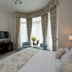 Park International Hotel London guest room with bay window seating, desk, TV and blue upholstered bed