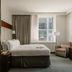 Club Quarters Hotel Faneuil Hall, Boston guest room with king bed, armchair, and city-view windows