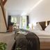 Dom Hotel Augsburg room with two twin beds, seating area, and open balcony doors to greenery