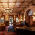 The Hotel Chelsea in New York lobby with chandelier, wood paneling, arched windows, and patterned rugs