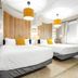 Canario Lagoon Hotel San Juan guest room with two beds, wood accent wall and hanging pendant lights