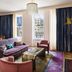 The Hotel Chelsea in New York living room with sofa, coffee table, colorful rug and city view