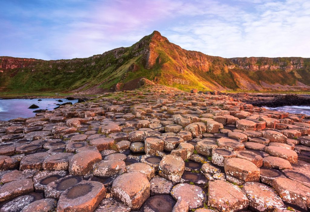 Impressive interlocking basalt columns of the Giant's Causeway on the coast surrounded by cliffs.