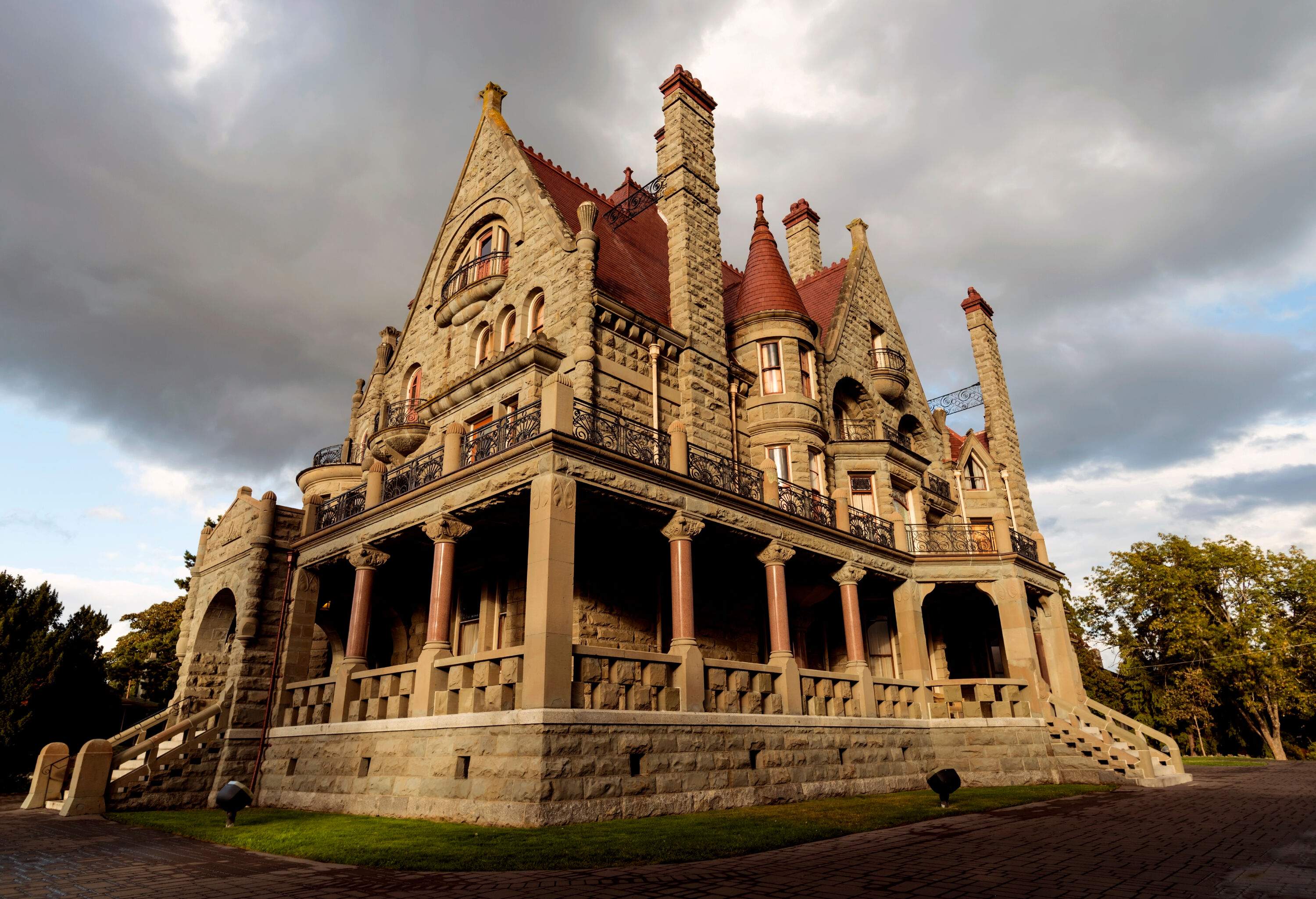 Craigdarroch Castle is a Scottish Baronial mansion with a recessed entrance, rusticated walls, cylindrical turrets with conical roofs, and outdoor halls.